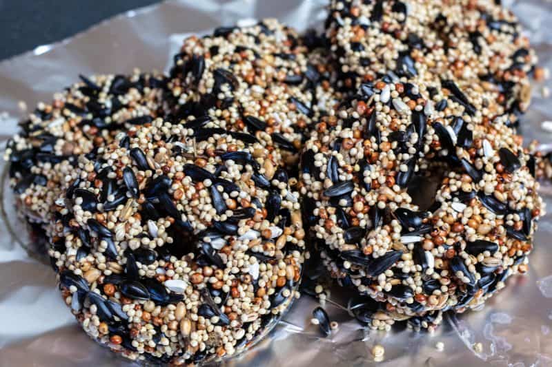 Stack of birdseed ornaments laying on foil waiting to be strung