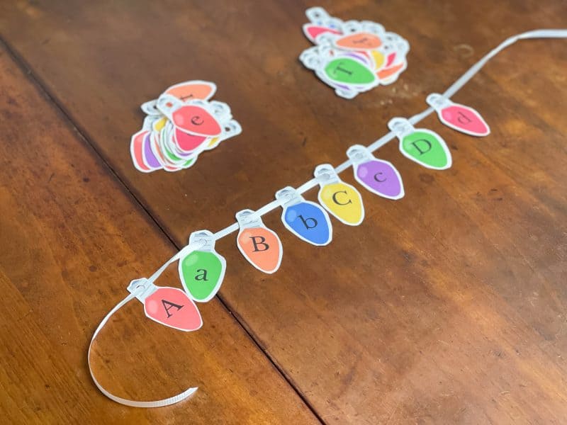 Paper Christmas lights with the alphabet printed on them strung in alphabetical order.