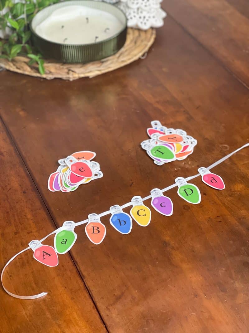 Paper Christmas lights with the alphabet printed on them strung in alphabetical order.