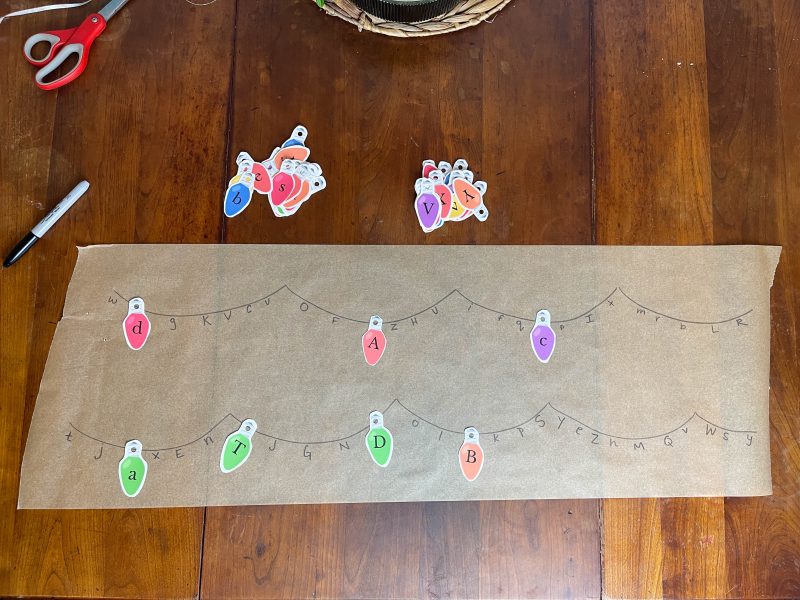 Match the Christmas Lights Activity.Brown parchment paper with the alphabet written on it. Paper Christmas lights with alphabet matching the letters.