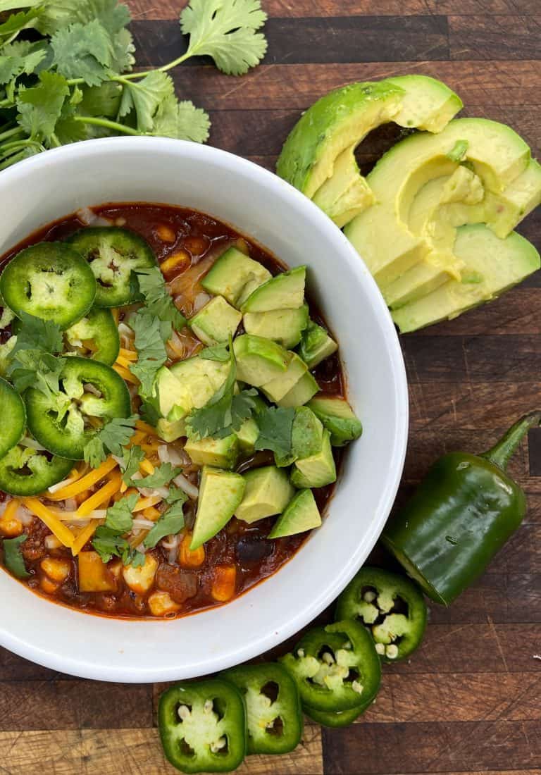 Blow of chili topped with jalapeño, cilantro, avocado, and cheese