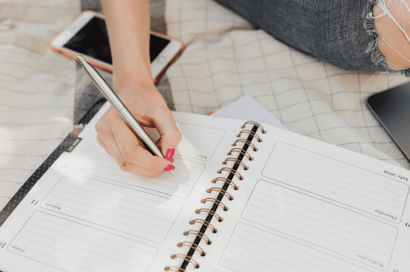 Woman's hand with a pen writing in a planner